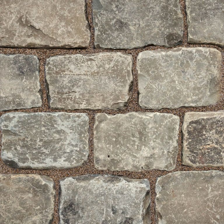 Best close-up image for Reclaimed European Sandstone Cobblestones. The surface finish shown is . Dominant colors shown are gray and tan; with beige, brown, green, orange/rust, purple, white and cream secondaries. Exhibits "movement" and the color mix creates a warm feeling. Regular, blotched and cloudy color patterns.