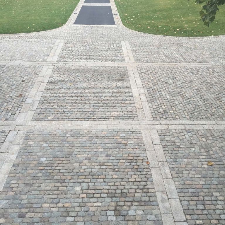 Application image for Reclaimed European Sandstone Cobblestones. The image shows this material being used in a driveway pavers application. The surface finish shown is . The dominant color shown is gray. The color mix creates a warm feeling.