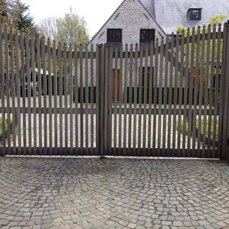 Application image for Reclaimed European Sandstone Cobblestones. The image shows this material being used in a driveway pavers application. The surface finish shown is . Dominant colors shown are brown and gray; with black, purple, white and tan secondaries. The color mix creates a warm feeling. Regular color pattern.