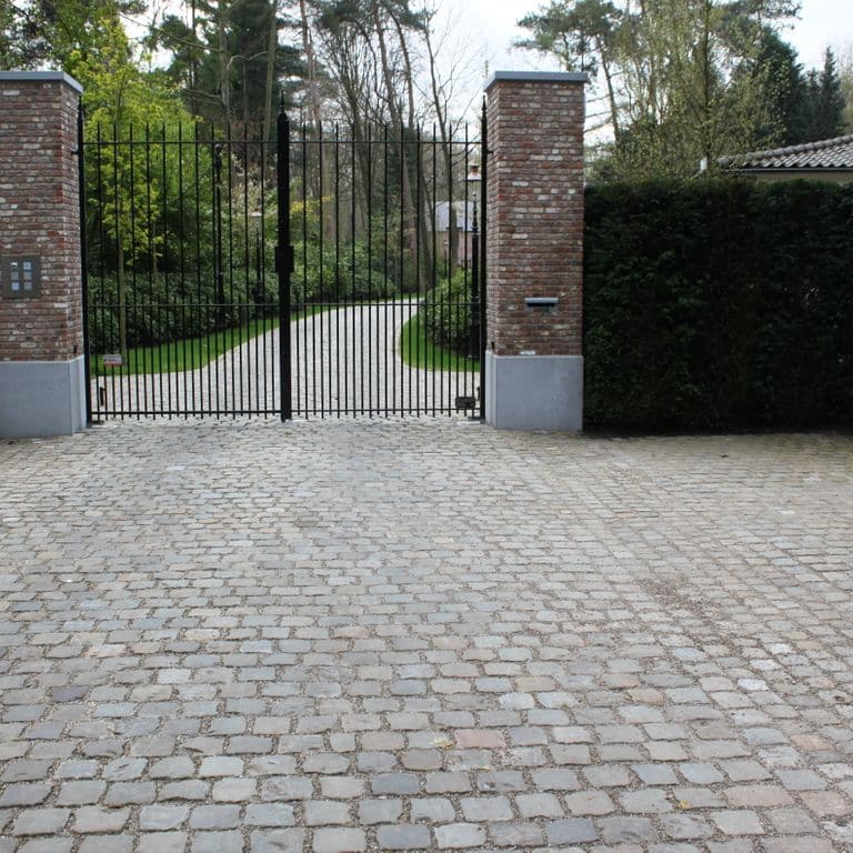 Application image for Reclaimed European Sandstone Cobblestones. The image shows this material being used in a driveway pavers application. The surface finish shown is . The dominant color shown is gray. The color mix creates a warm feeling.