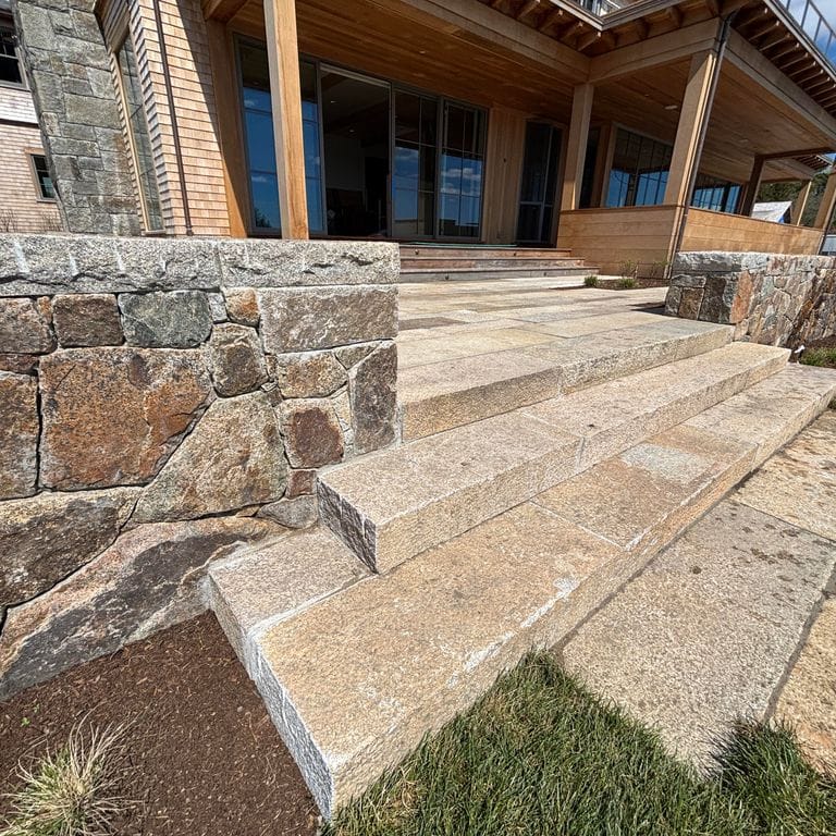 Application image for Reclaimed Footworn Granite. The image shows this material being used in a monolithic steps application. The surface finish shown is . Dominant colors shown are beige and tan; with beige, brown, green, orange/rust, pink, white, tan and cream secondaries. Speckled, blotched and cloudy color patterns.