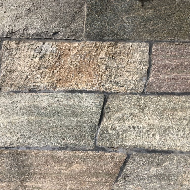 Close-up image for Reclaimed Quartzite Plank Pavers. The surface finishes shown are split-face with flat plane and weathered. Dominant colors shown are beige, brown and gray; with green, orange/rust, purple, white, tan and cream secondaries. Exhibits "movement" and the color mix creates a warm feeling. Regular, blotched and linear color patterns.