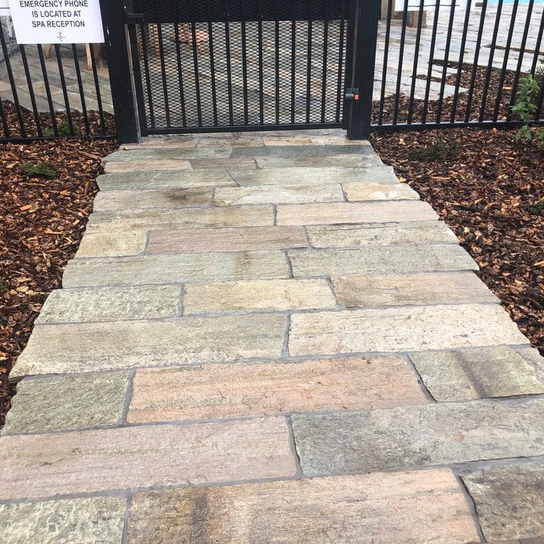 The image shows this material being used in a path pavers application. Dominant colors shown are beige, gray and tan; with brown, orange/rust, white and cream secondaries. The color mix creates a warm feeling. Regular and fine speckled color patterns.