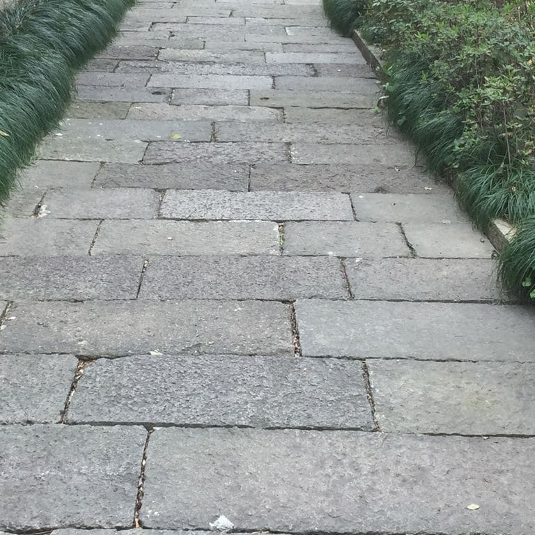 The image shows this material being used in a path pavers application. The dominant color shown is gray. The color mix creates a cool feeling. Solid and fine speckled color patterns.