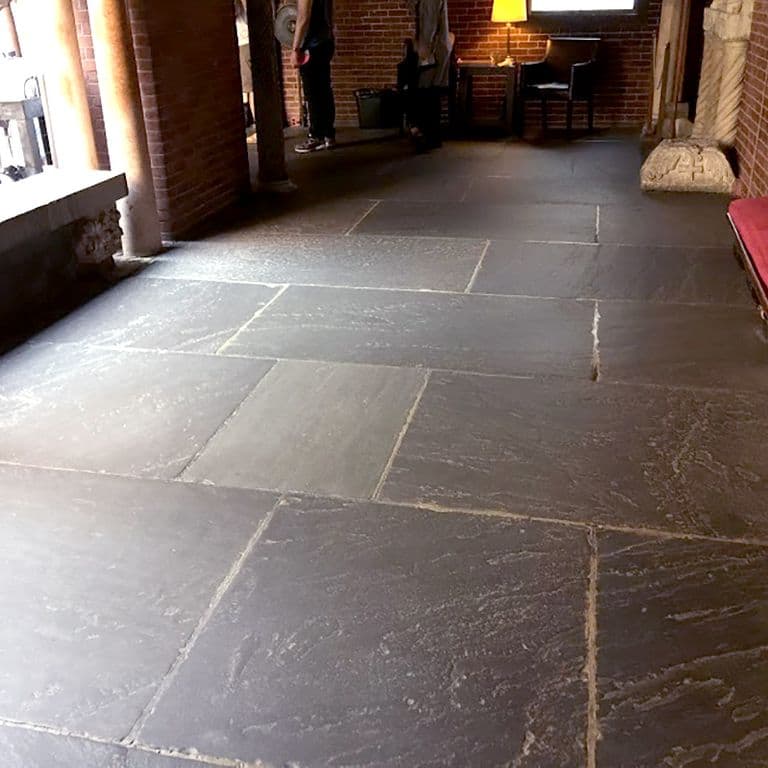 The image shows this material being used in an interior floor application. Dominant colors shown are brown, gray and purple; with beige and tan secondaries. Solid, random, veined and streaked color patterns.