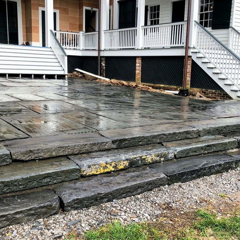 Feature image for Reclaimed Bluestone Curbstone. The image shows this material being used in a monolithic steps application. The dominant color shown is gray; with black, brown, green, orange/rust, purple and tan secondaries. The color mix creates a cool feeling. Regular color pattern.