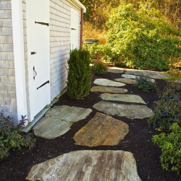 The image shows this material being used in a path pavers application. Dominant colors shown are brown and gray; with beige, orange/rust, yellow and cream secondaries. Regular, linear and streaked color patterns.