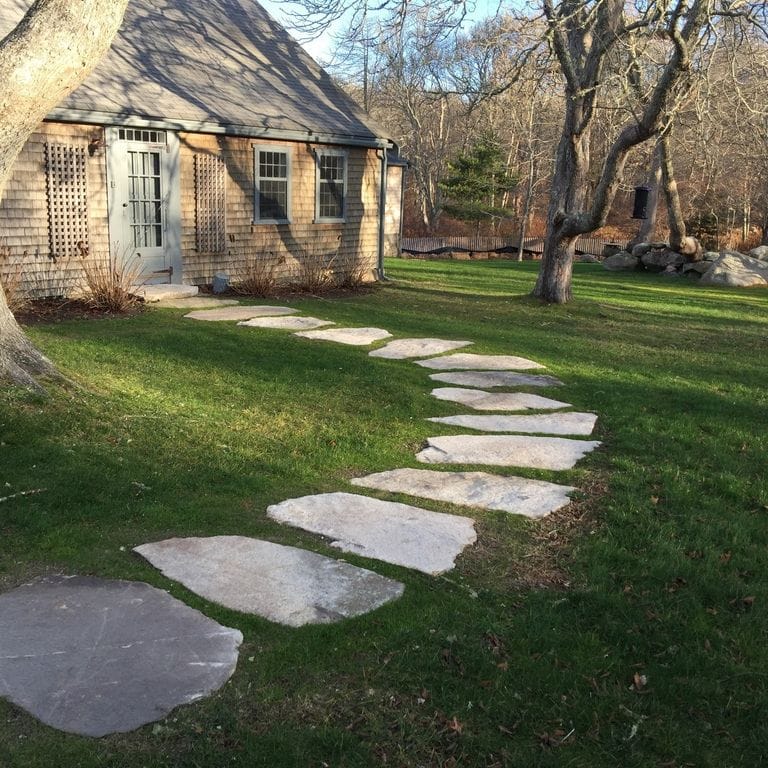 The image shows this material being used in a path pavers application. The dominant color shown is gray; with a tan secondary. Regular color pattern.