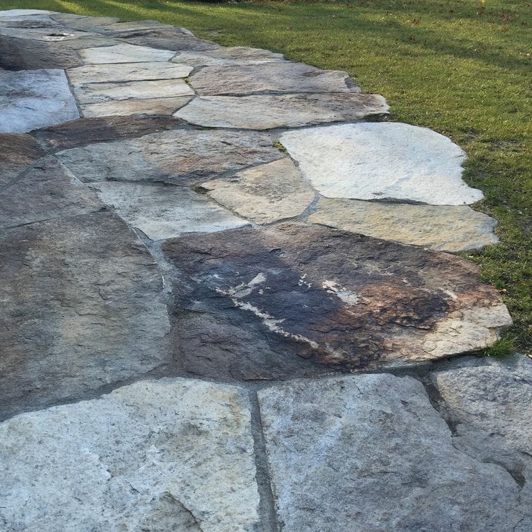 The image shows this material being used in a patio pavers application.