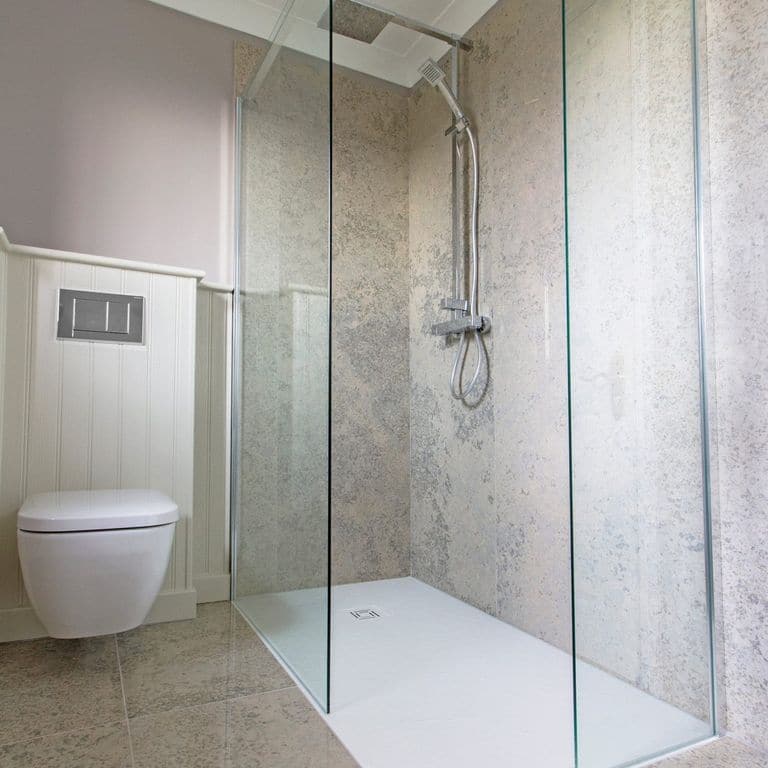 Feature image for Mountain Hard Blue Limestone. The image shows this material being used for interior floor and bath tub &amp; shower. The surface finish shown is polished. The dominant color shown is gray. The color mix creates a cool feeling. Blotched color pattern.