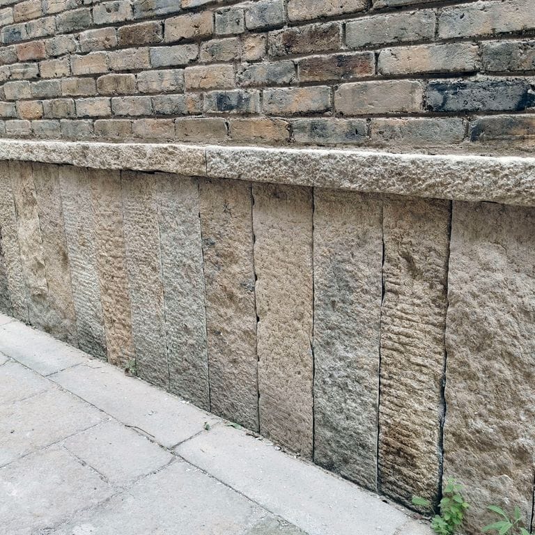 Application image for Reclaimed Granite Plank Veneer. The image shows this material being used in a full bed veneer application. The surface finish shown is . The dominant color shown is gray. The color mix creates a cool feeling. Regular color pattern.