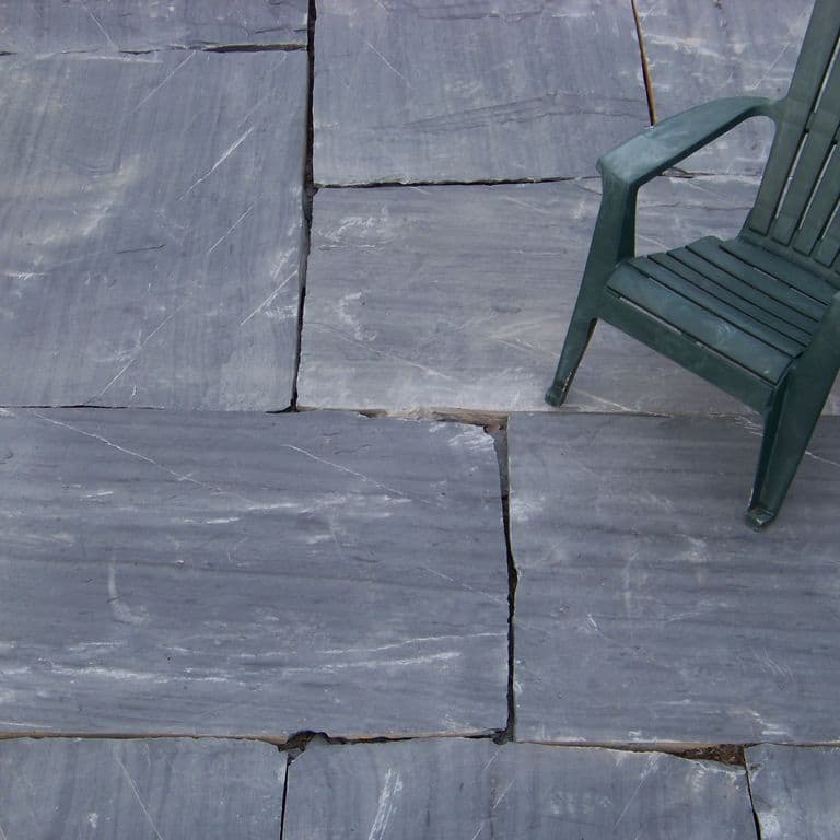The image shows this material being used in a patio pavers application. Dominant colors shown are blue and gray; with black and white secondaries. Exhibits "movement" and the color mix creates a cool feeling. Regular and streaked color patterns.
