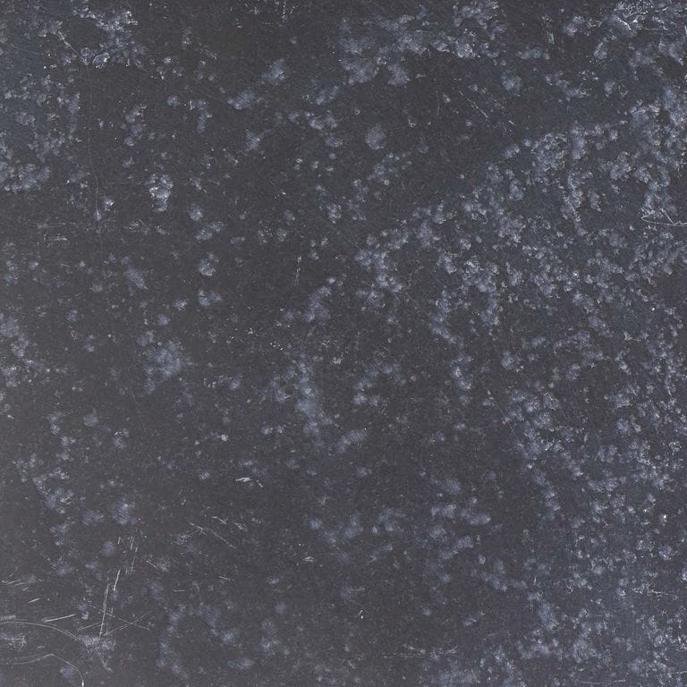 Color/Finish variation image for Bahama Black Limestone. The surface finish shown is antiqued. The dominant color shown is gray; with black and green secondaries. Exhibits "movement" and the color mix creates a cool feeling. Speckled and blotched color patterns.