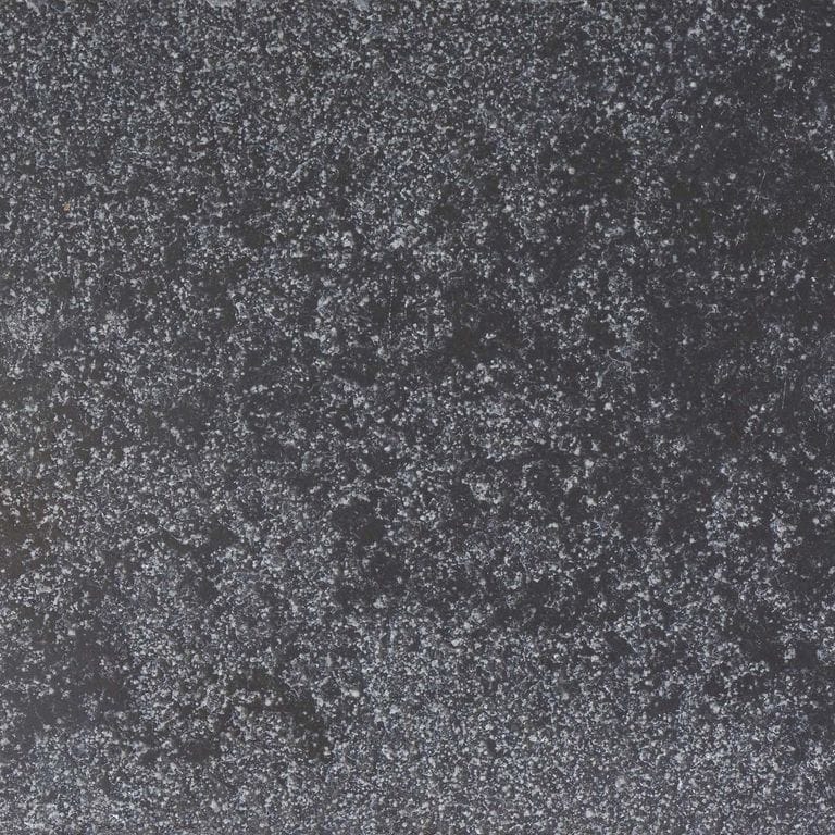 Color/Finish variation image for Bahama Black Limestone. The surface finish shown is bush hammered. Dominant colors shown are black and gray; with a purple secondary. The color mix creates a cool feeling. Speckled and blotched color patterns.