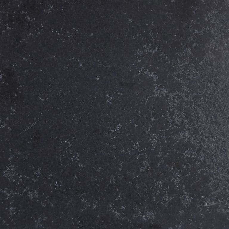 Close-up image for Bahama Black Limestone. The surface finish shown is antiqued. The dominant color shown is black; with blue and gray secondaries. Exhibits "movement" and the color mix creates a cool feeling. Regular, fine speckled and blotched color patterns.