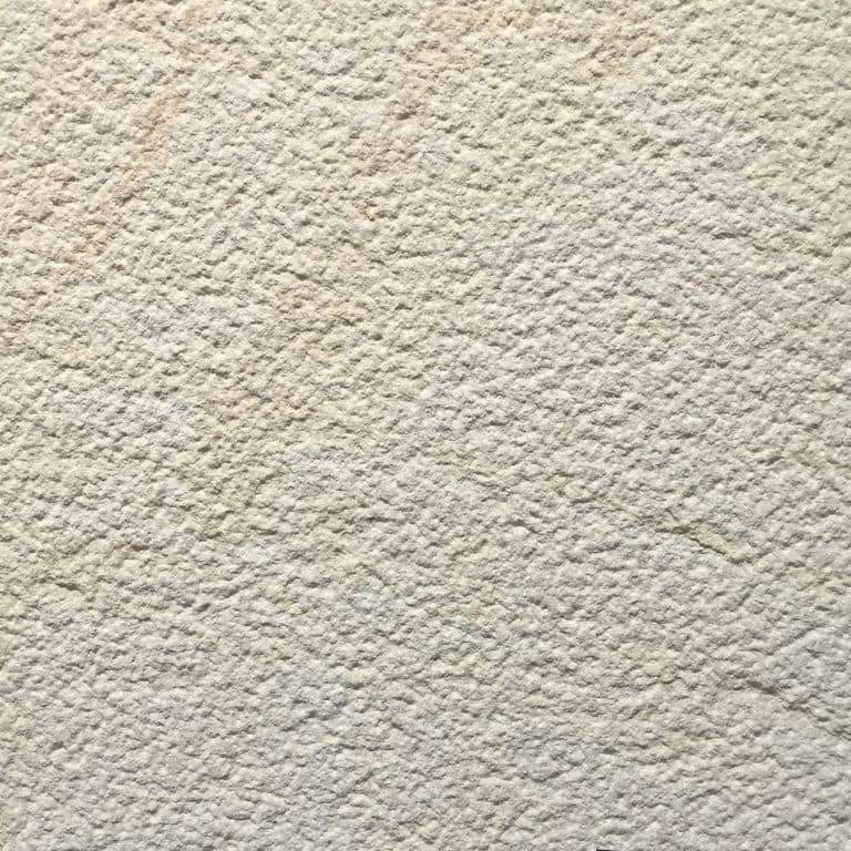 Color/Finish variation image for Portland White Sandstone. The surface finish shown is bush hammered. Dominant colors shown are beige and cream; with gray, white and tan secondaries. The color mix creates a warm feeling. Speckled color pattern.