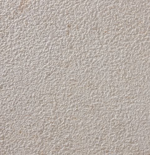 Color/Finish variation image for Portuguese Pacific Beige Limestone. The surface finish shown is bush hammered. The dominant color shown is tan; with beige, purple and white secondaries. Regular and speckled color patterns.