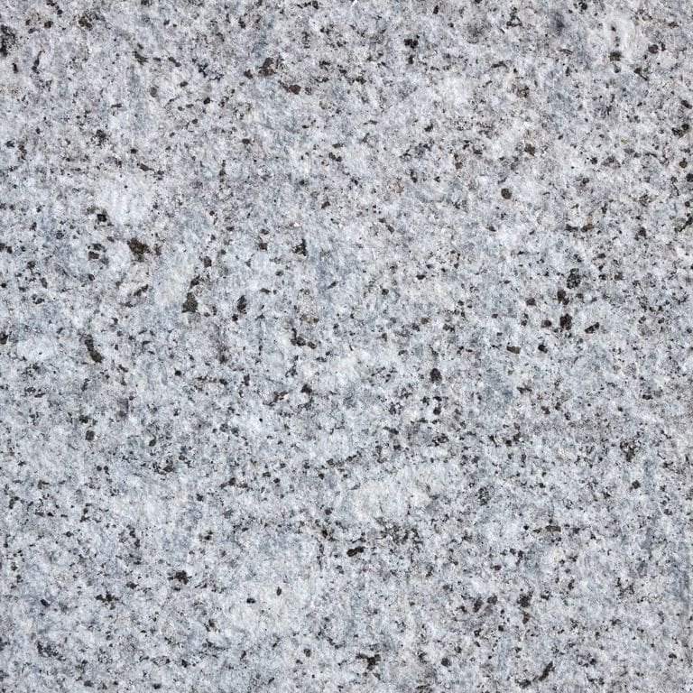 Best close-up image for Granite - Colonial Blue. The surface finish shown is flamed. Dominant colors shown are blue and gray. The color mix creates a cool feeling. Speckled and blotched color patterns. Contains some mica and mineral inclusions.