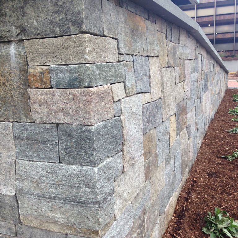 The image shows this material being used in a landscape wallstone application.