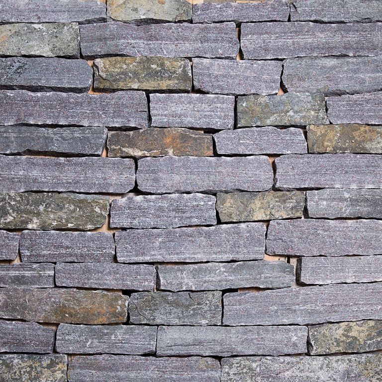 Close-up image for Dolph Pond Granite. The surface finishes shown are split-face and weathered. Dominant colors shown are blue and gray; with brown, orange/rust, purple, white and tan secondaries. Exhibits "movement". Fine speckled, blotched and linear color patterns.