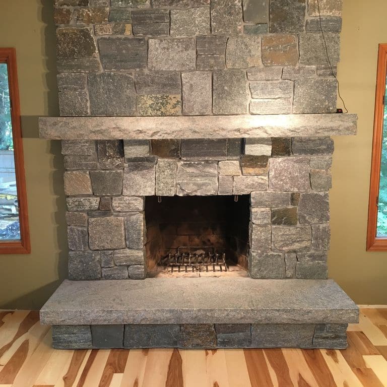 Application image for Granite - Dolph Pond. The image shows this material being used for fireplace hearth and fireplace mantel. The dominant color shown is gray.