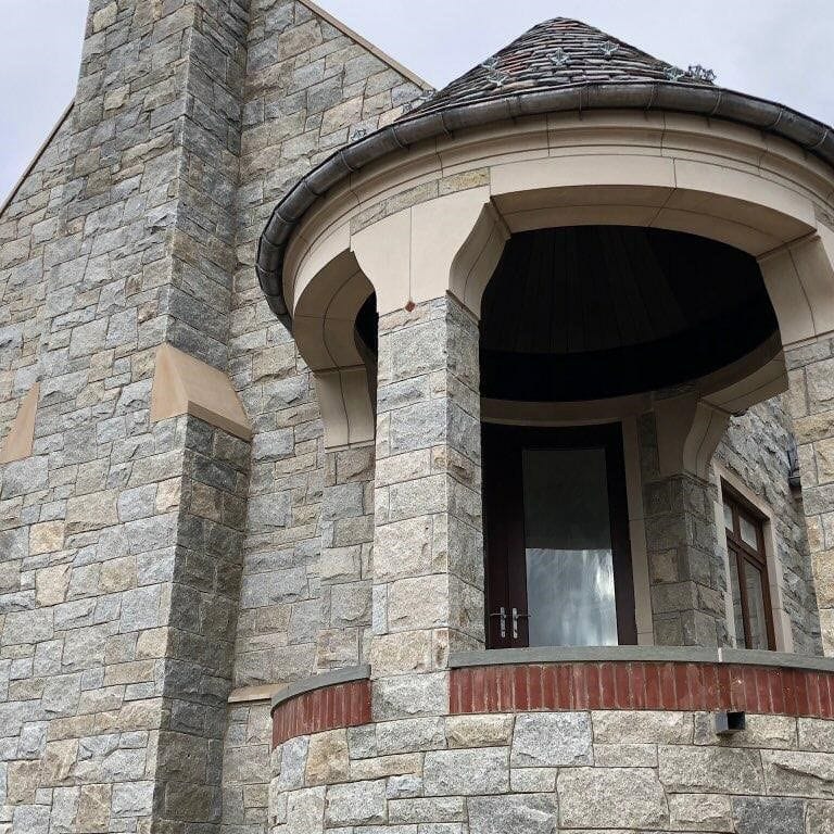 Feature image for Dusty Rose Granite. The image shows this material being used for full bed veneer and thin veneer. The dominant color shown is gray; with beige, brown, white and tan secondaries. The color mix creates a warm feeling. Regular, speckled and blotched color patterns.