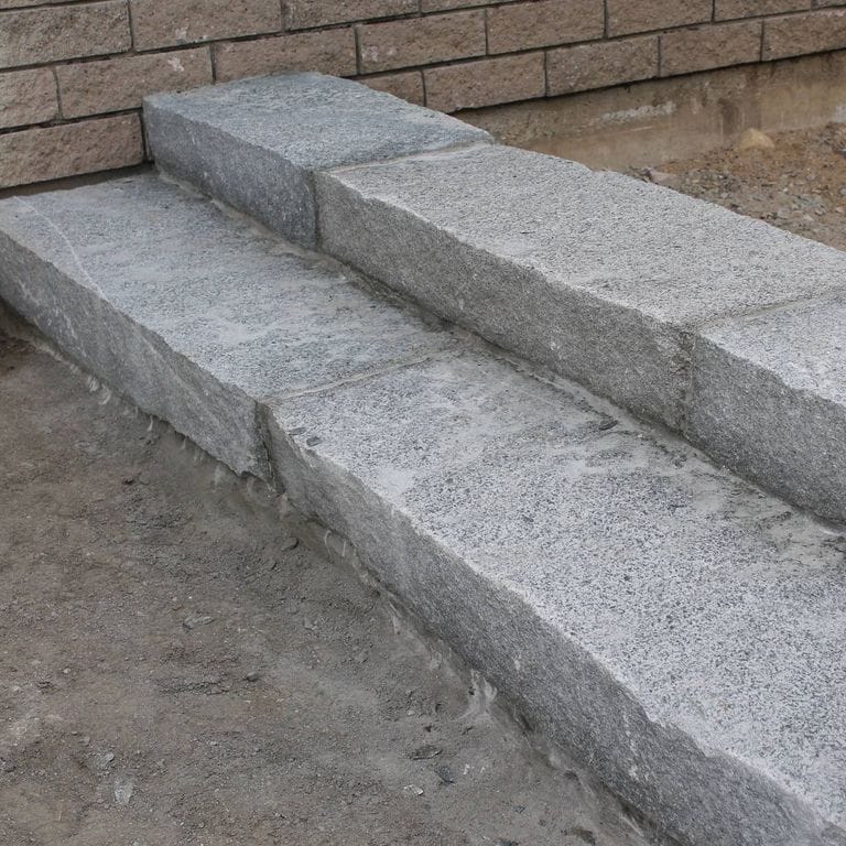 Application image for Dusty Rose Granite. The image shows this material being used in a monolithic steps application. This is a building and landscape stone for indoor and outdoor commercial and residential applications. Suitable for general use, freeze-thaw conditions, low heat absorption surfaces and low slipperiness surfaces situations. Relatively moderate in price.