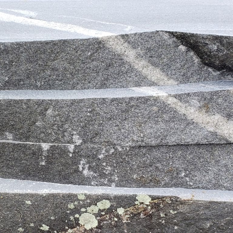 Close-up image for Fitzwilliam Granite. The surface finishes shown are natural and sawn. The dominant color shown is gray; with a gray secondary. Exhibits "movement" and the color mix creates a cool feeling. Speckled, fine speckled and veined color patterns. Contains mineral inclusions.