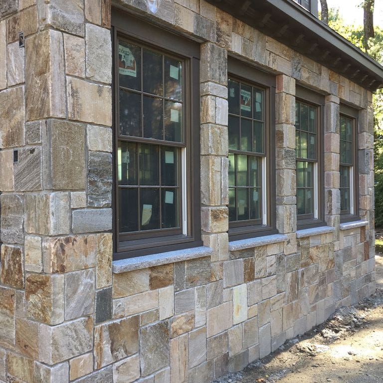 Feature image for Sterling Tan Quartzite. The image shows this material being used in a thin veneer application. Dominant colors shown are gray and tan; with beige, black, brown and cream secondaries. The color mix creates a warm feeling. Random, blotched, swirled and streaked color patterns.