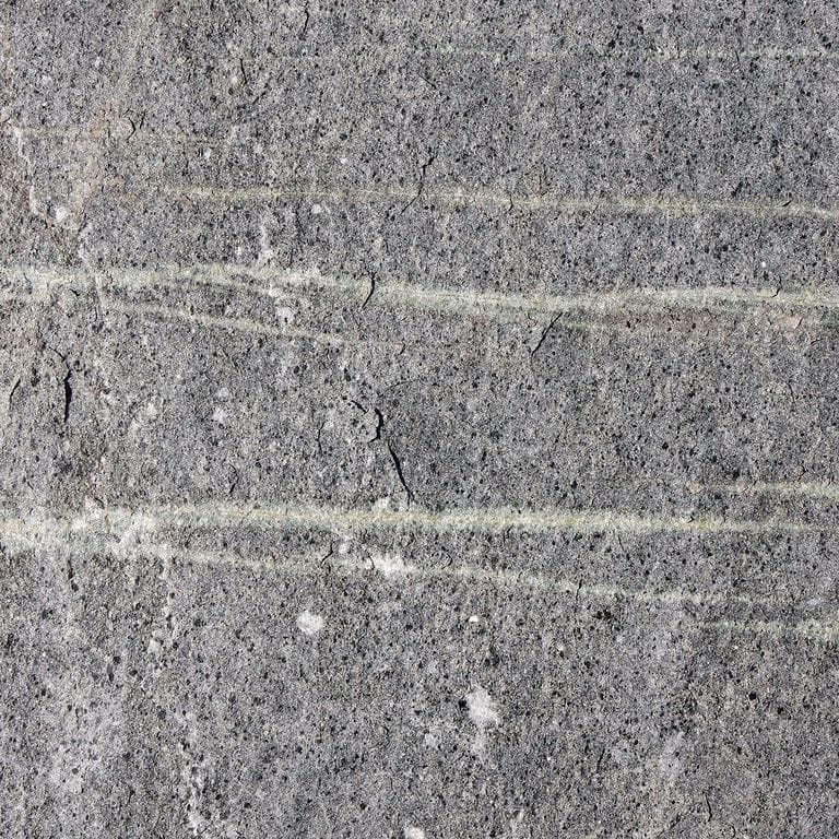 Color/Finish variation image for American Mist Granite. The surface finish shown is flamed. The dominant color shown is gray; with black, blue, brown, green, purple and white secondaries. Exhibits "movement" and the color mix creates a cool feeling. Random, fine speckled and veined color patterns. Contains some mica and mineral inclusions.