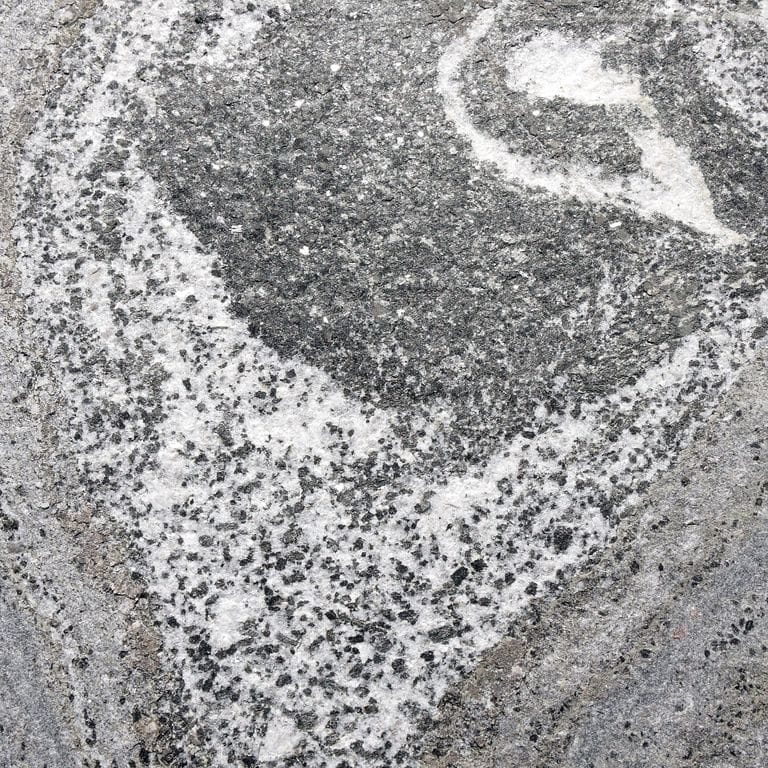 Color/Finish variation image for American Mist Granite. The surface finish shown is flamed. The dominant color shown is gray; with beige, black, blue, brown, green, pink, purple, white and cream secondaries. Exhibits "movement" and the color mix creates a cool feeling. Random, fine speckled and swirled color patterns. Contains some mica and mineral inclusions.
