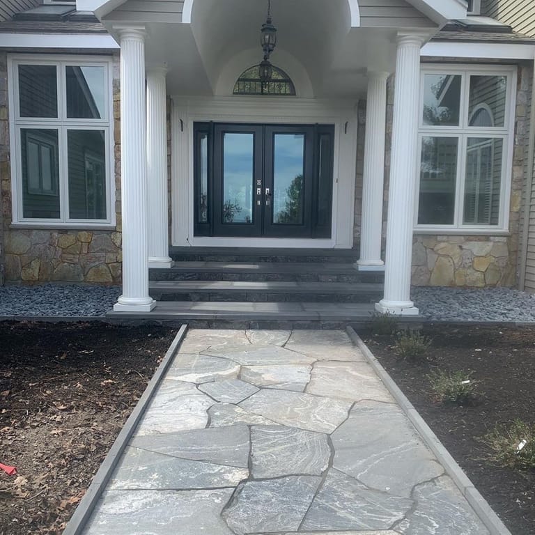 Feature image for American Mist Granite. The image shows this material being used in a path pavers application. The dominant color shown is gray; with beige and white secondaries. Exhibits "movement" and the color mix creates a cool feeling. Swirled and streaked color patterns.