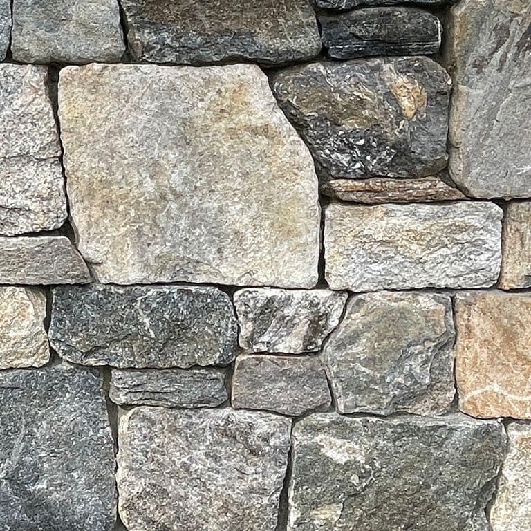 Best close-up image for Liberty Hill Granite. The image shows this material being used in a full bed veneer application. The surface finish shown is split-face. The dominant color shown is gray; with brown, green, orange/rust, white, tan and cream secondaries. Exhibits "movement". Regular and random color patterns.