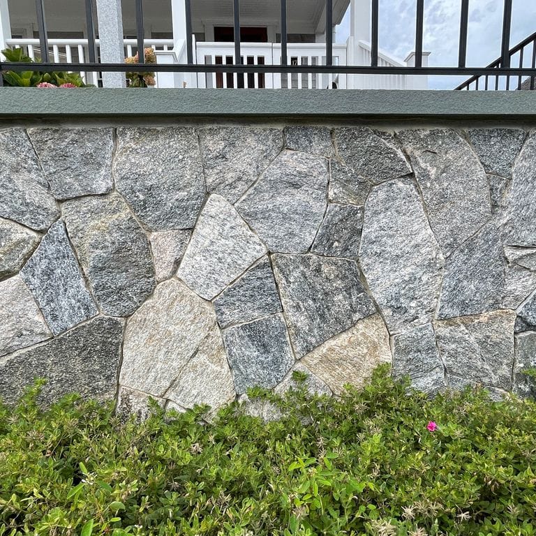 Feature image for Granite - Liberty Hill. The image shows this material being used in a full bed veneer application. The surface finish shown is split-face. The dominant color shown is gray; with beige, blue, brown, green, white, tan and cream secondaries. Regular, streaked and random color patterns.