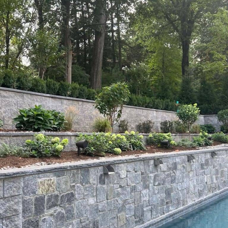 Application image for Granite - Spruce Mountain. The image shows this material being used in a retaining wall application. The dominant color shown is gray. The color mix creates a warm feeling. Speckled and random color patterns.