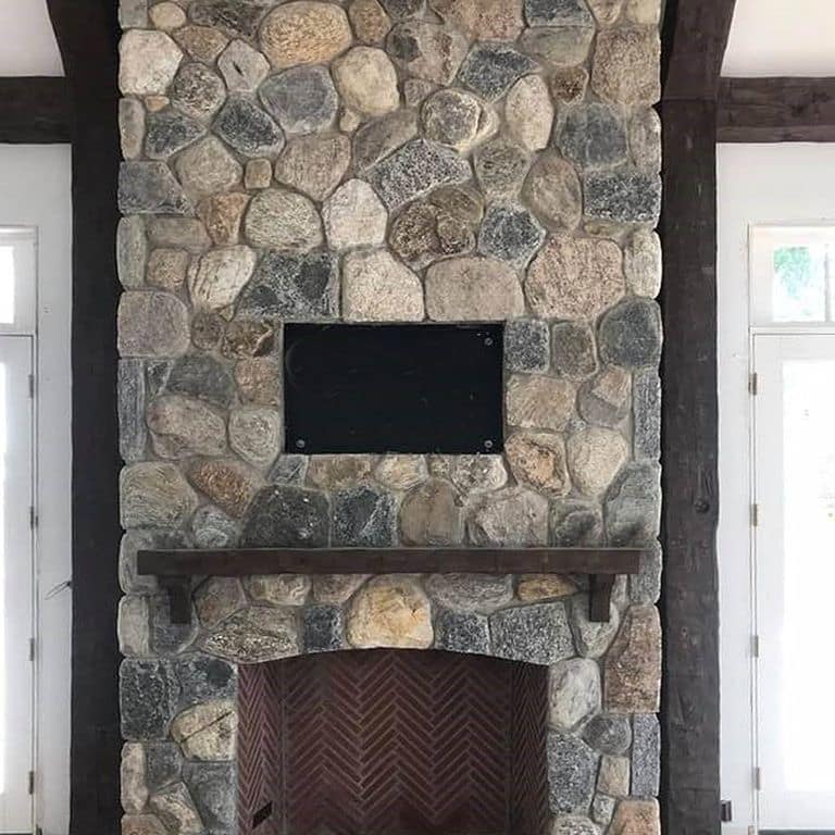 Feature image for River Rounds- Cedar Creek. The image shows this material being used for fireplace surround, thin veneer and interior cladding. The surface finish shown is natural. Dominant colors shown are brown, gray and tan; with beige, orange/rust and purple secondaries. The color mix creates a warm feeling. Regular, speckled and random color patterns.