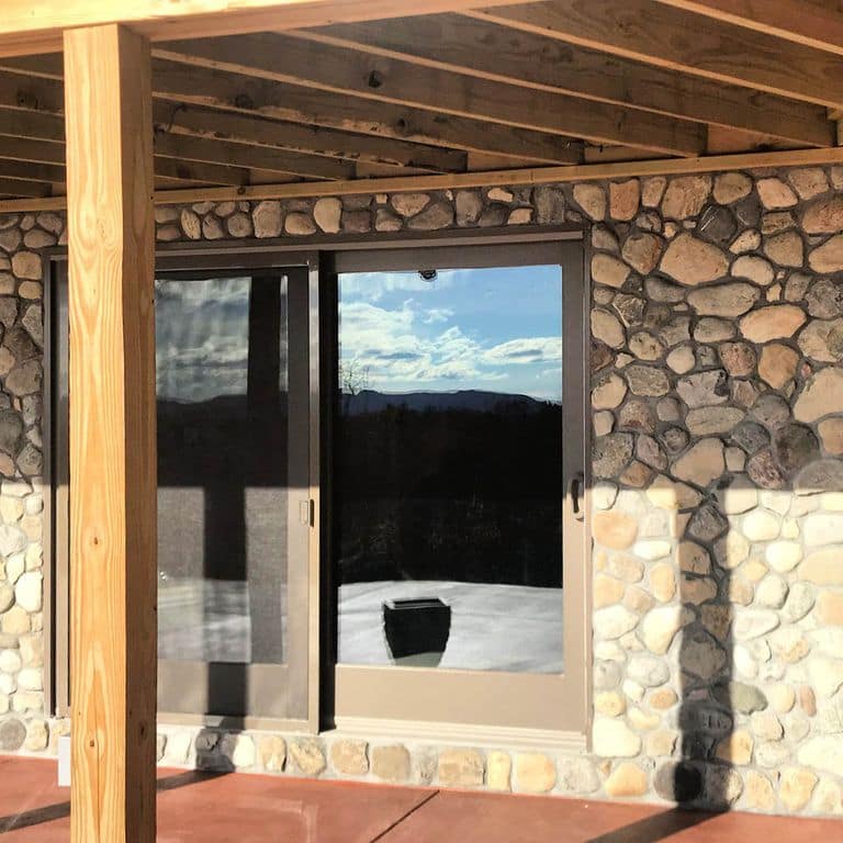 Application image for Newport River Rounds. The image shows this material being used in a thin veneer application. The surface finish shown is natural. Dominant colors shown are brown, gray and tan; with beige, blue, white and cream secondaries. Regular color pattern.