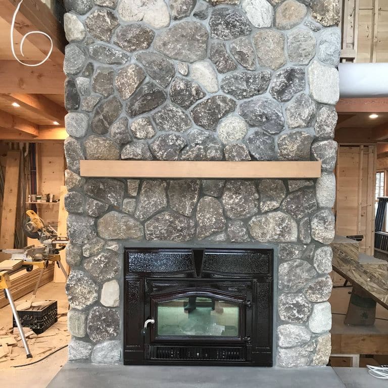 Application image for Fieldstone - Old New England Round. The image shows this material being used for fireplace mantel, thin veneer and interior cladding. The dominant color shown is gray. The color mix creates a warm feeling.