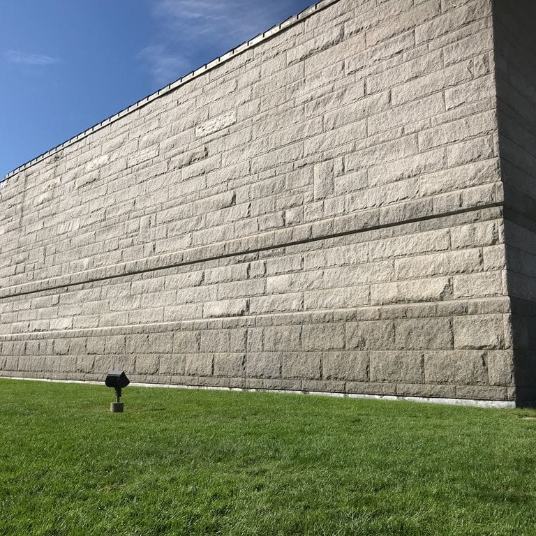 Application image for Deer Isle Granite. The image shows this material being used in a full bed veneer application. The surface finish shown is split-face. The dominant color shown is gray.