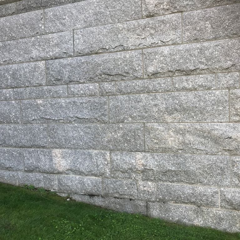 Application image for Deer Isle Granite. The image shows this material being used in a full bed veneer application. The surface finish shown is split-face. The dominant color shown is gray. The color mix creates a cool feeling.