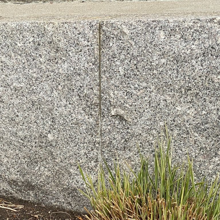 Application image for Deer Isle Granite. The image shows this material being used in a landscape wallstone application. Dominant colors shown are gray and pink. The color mix creates a warm feeling. Speckled color pattern.