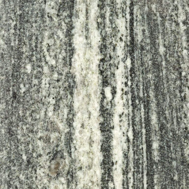 Close-up image for Galactic Granite. The surface finish shown is polished. The dominant color shown is gray; with beige, black, green, white and cream secondaries. Exhibits "movement". Speckled, linear and streaked color patterns. Contains mineral inclusions.