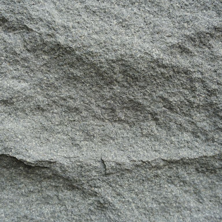 Color/Finish variation image for Basalt - Ankar Gray. The surface finish shown is rockfaced. The dominant color shown is gray; with a green secondary. Exhibits "movement" and the color mix creates a cool feeling. Regular, fine speckled and speckled color patterns.