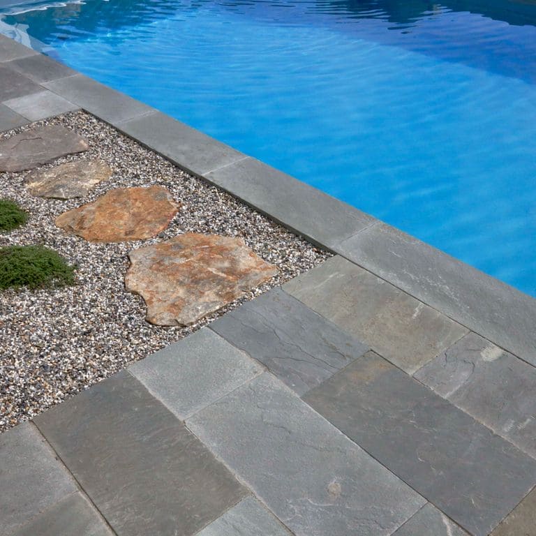 Application image for Blue/Gray Bluestone - Natural Cleft. The image shows this material being used for pool coping and pool deck pavers. The surface finish shown is natural cleft. Dominant colors shown are blue and gray. The color mix creates a cool feeling.