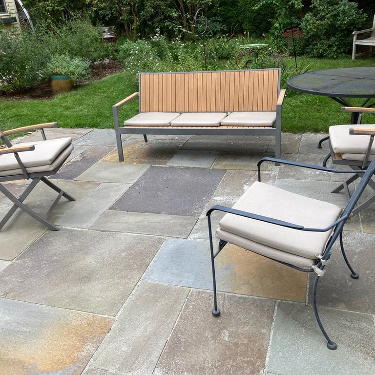 Application image for Bluestone Natural Cleft - Gunmetal. The image shows this material being used in a patio pavers application. The surface finish shown is natural cleft. The dominant color shown is gray; with brown, green and orange/rust secondaries. The color mix creates a cool feeling.