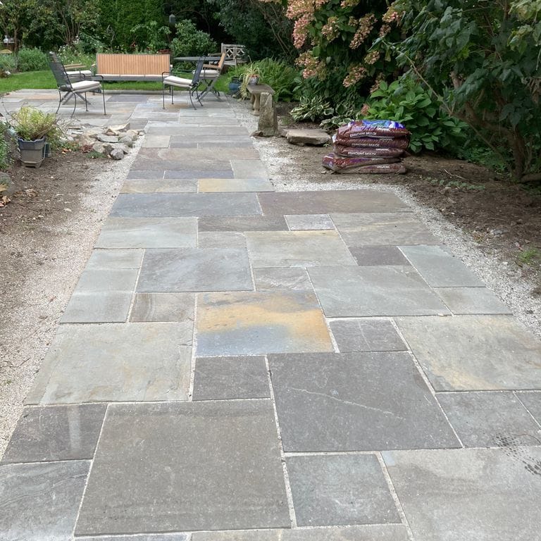 Application image for Bluestone Natural Cleft - Gunmetal. The image shows this material being used for path pavers and patio pavers. The surface finish shown is natural cleft. The dominant color shown is gray. The color mix creates a cool feeling. Regular, blotched and random color patterns.
