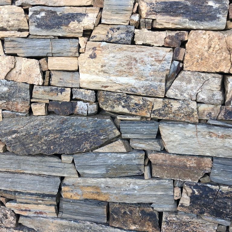 Close-up image for Oxidized Shale. The surface finish shown is natural. The dominant color shown is gray; with beige, black, blue, brown, green, orange/rust, purple, white, tan and cream secondaries. Exhibits "movement" and the color mix creates a warm feeling. Random, speckled, blotched and linear color patterns.