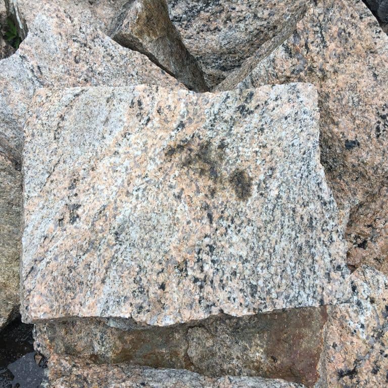 Close-up image for Hudson Granite. The dominant color shown is gray; with beige, black, blue, brown, green, orange/rust, pink, purple, white, tan and cream secondaries. Exhibits "movement" and the color mix creates a warm feeling. Random, coarse speckled and streaked color patterns.