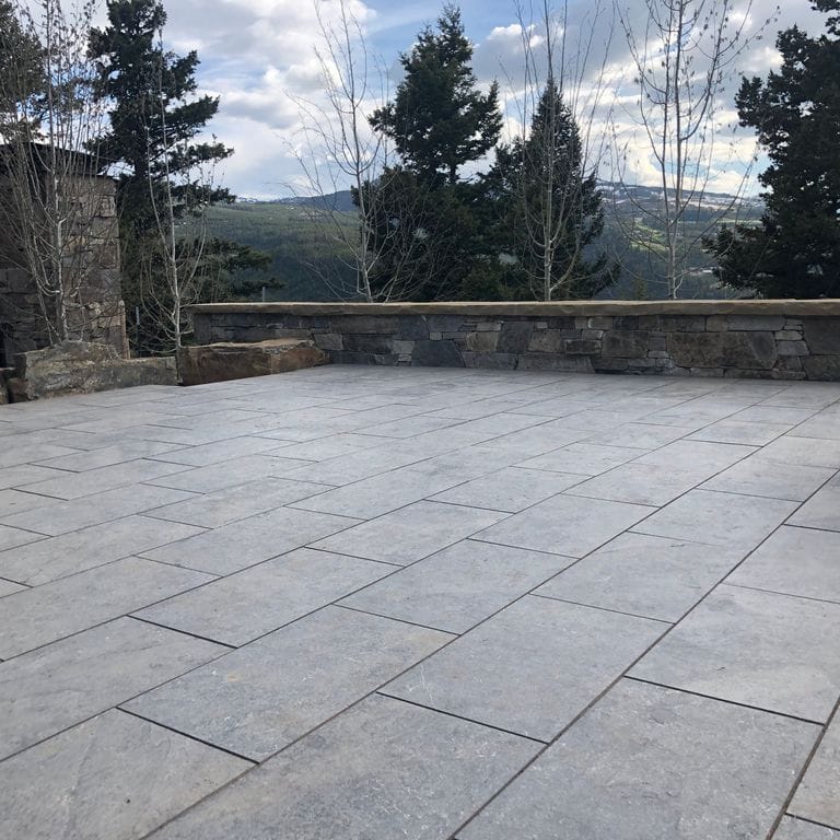 Application image for Limestone - Highland. The image shows this material being used in a patio pavers application. The surface finish shown is flamed. The dominant color shown is gray. The color mix creates a cool feeling. Regular and cloudy color patterns.