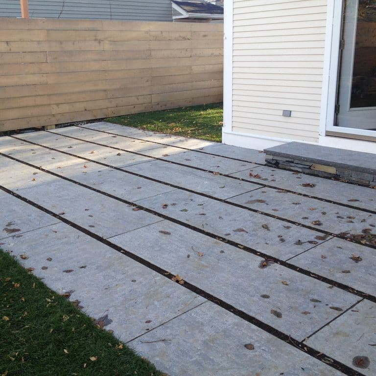 Application image for Highland Limestone. The image shows this material being used for patio pavers and treads. The surface finish shown is flamed. The dominant color shown is gray. The color mix creates a cool feeling. Regular color pattern.